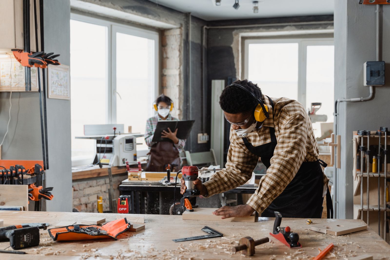 A man wearing ear protection works at a woodworking bench.