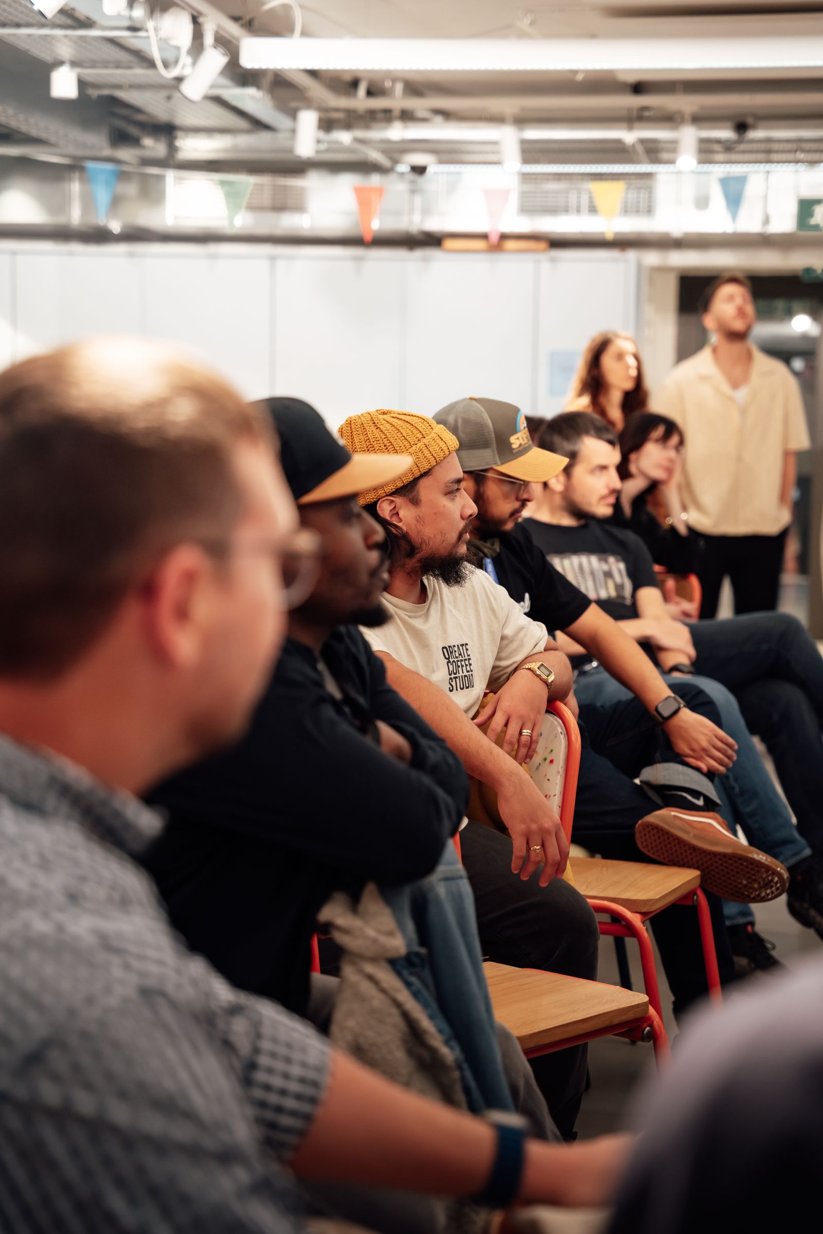 A group of men of different backgrounds and ages sit together listening during a community workshop